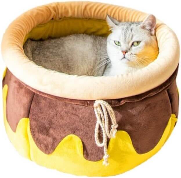 Cat lounging in a honey pot-shaped warm, soft pet bed with comfortable soft fabric and creative design.