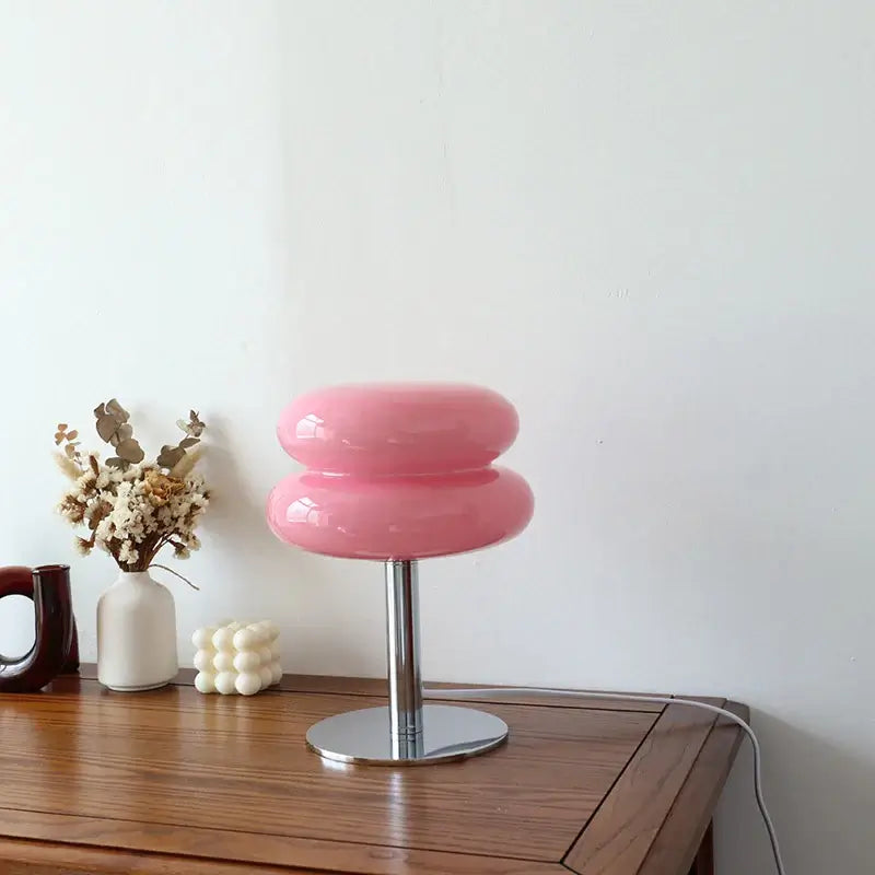 Pink Macaron glass table lamp on a wooden table, adding charm and warmth to stylish decor.