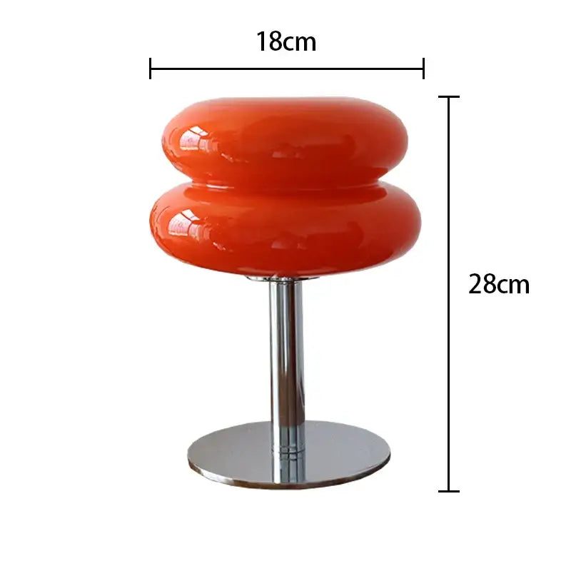 Macaron glass table lamp in vibrant orange, elegantly designed with a chrome base for stylish bedroom decor.