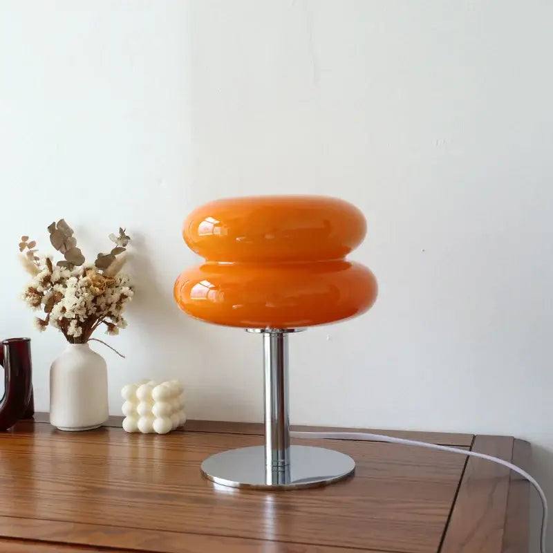 Vibrant orange Macaron glass table lamp on wooden table, perfect for adding warmth and style to any decor.