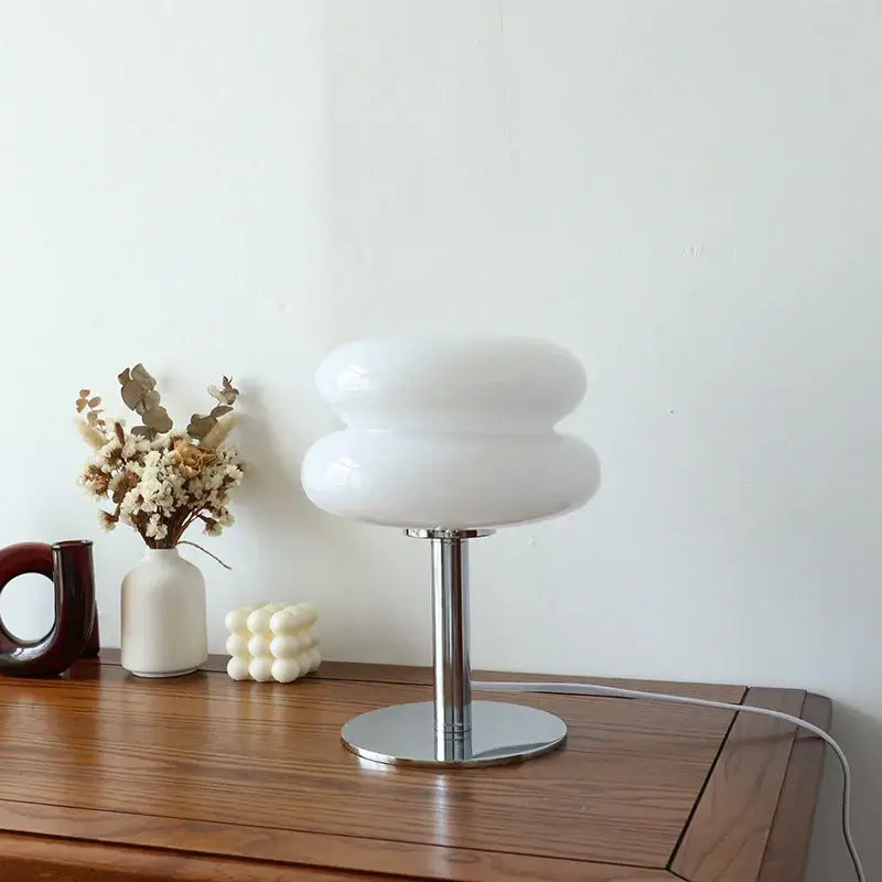 Modern Macaron Glass Table Lamp on a wooden table, showcasing its elegant design and warm, inviting glow. Perfect for bedroom decor.